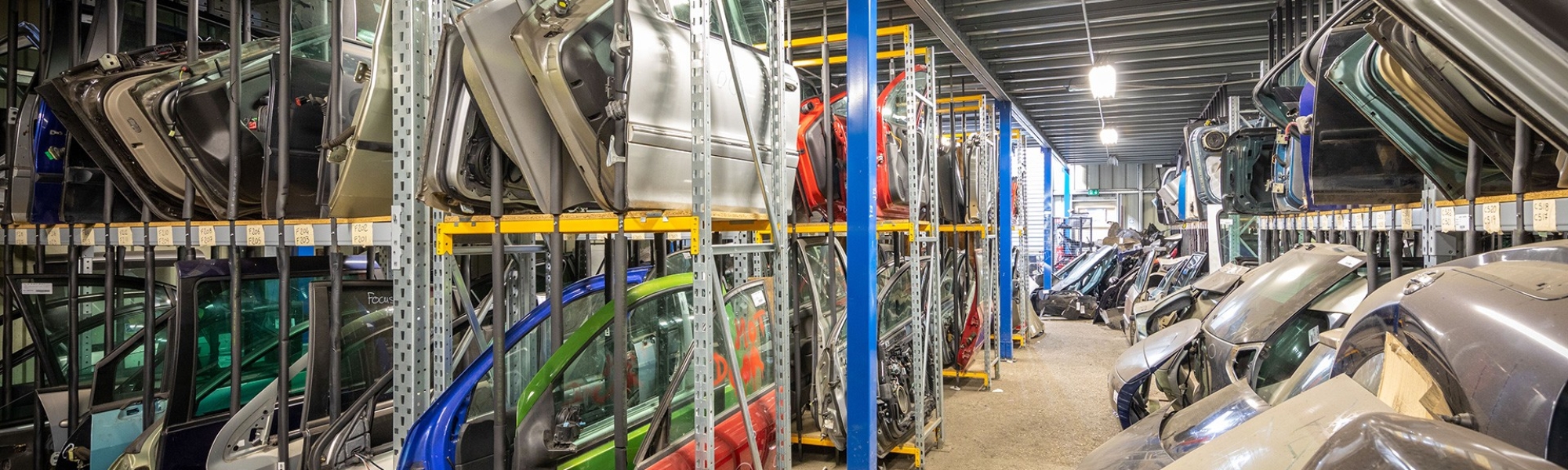 Almacenamiento de piezas de carrocería en un desguace en estanterías industriales Prorack+ con separadores