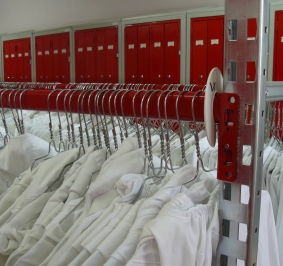Batas blancas almacenadas en estanterías Prorack+ en un vestuario común 
			