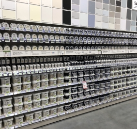 Latas de pintura expuestas en estanterías de una tienda de bricolaje
			