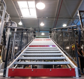 Escalera metálica instalada en un pabellón deportivo para acceder a una plataforma
			