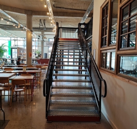 Escalera recta con rellano instalada en un restaurante
			