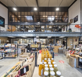 Plataforma metálica que soporta un espacio de coworking en una tienda de alimentación
			
