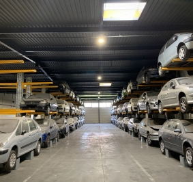 Almacén con coches almacenados en estanterías altas
			