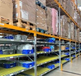 Almacenamiento de palés y cajas de plástico para picking en estanterías dinámicas de un almacén
			