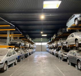  Almacén con coches almacenados en estanterías altas
			