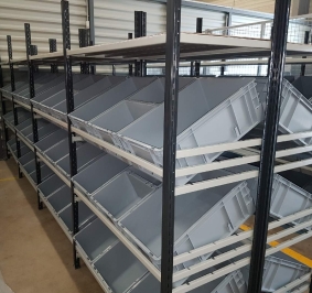 Estanterías inclinadas con papeleras en una empresa de servicios sanitarios
			