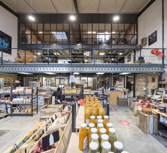 Plataforma metálica que soporta un espacio de coworking en una tienda de alimentación
                