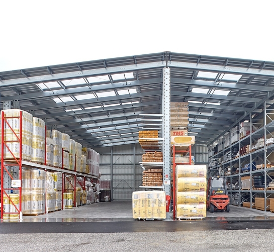 Almacén exterior de materiales, vista frontal, montado con estanterías cantiléver provistas de toldos translúcidos
                