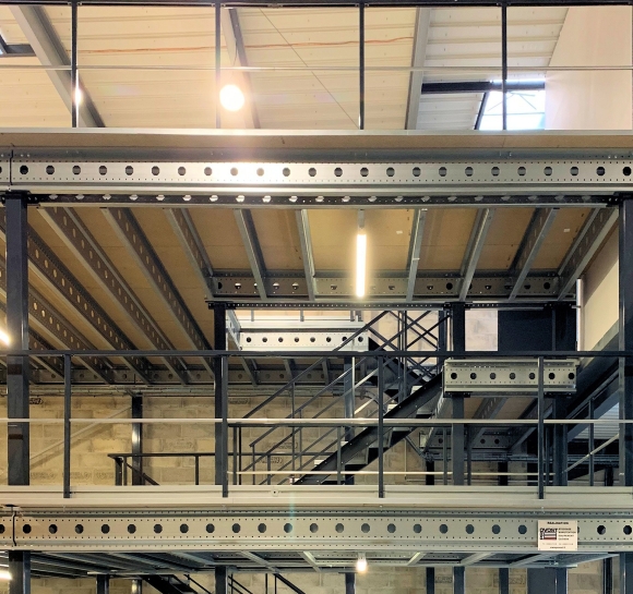 Escalera metálica doble que da acceso a varios niveles de una plataforma en un almacén]
		                    