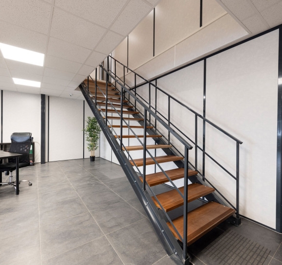 Escalera metálica con peldaños de madera instalada en local comercial para dar acceso al piso superior