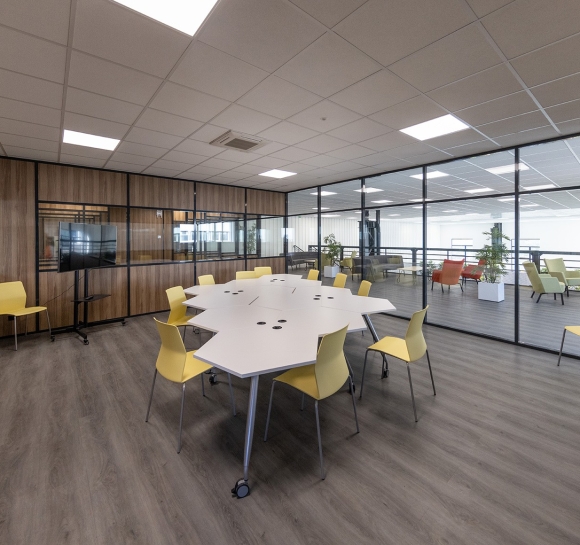 Sala de reuniones con mesas y sillas de diseño, situada sobre una plataforma de oficinas